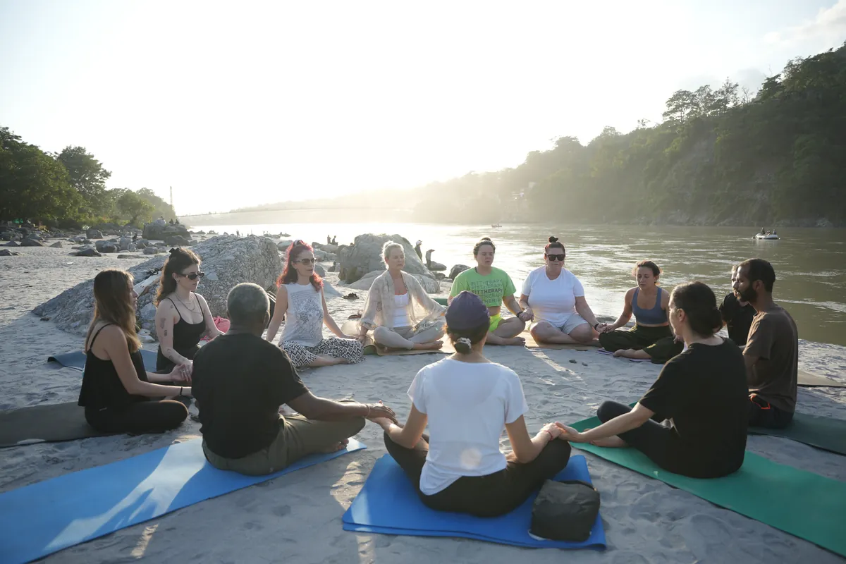 Students meditating together at sunrise on the bank of the Ganga in Rishikesh