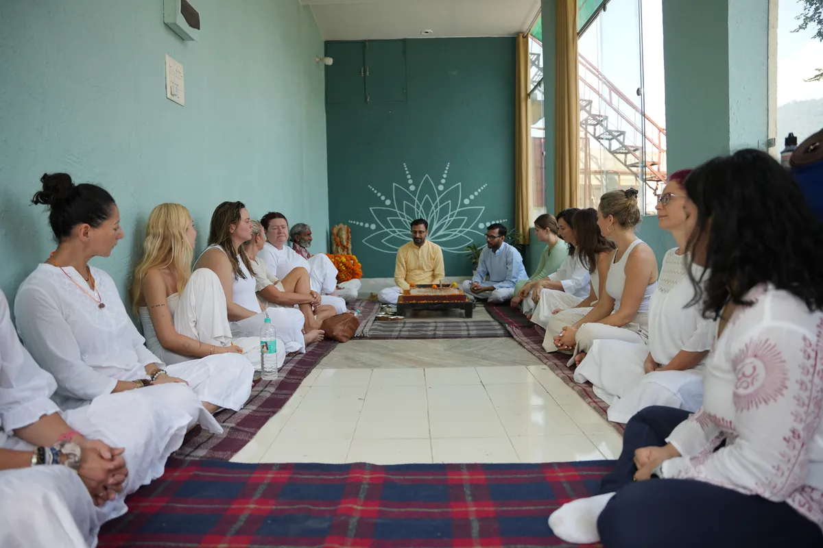 Students seated along the walls of the hall during satsang at Sri Yoga Ashram, Rishikesh