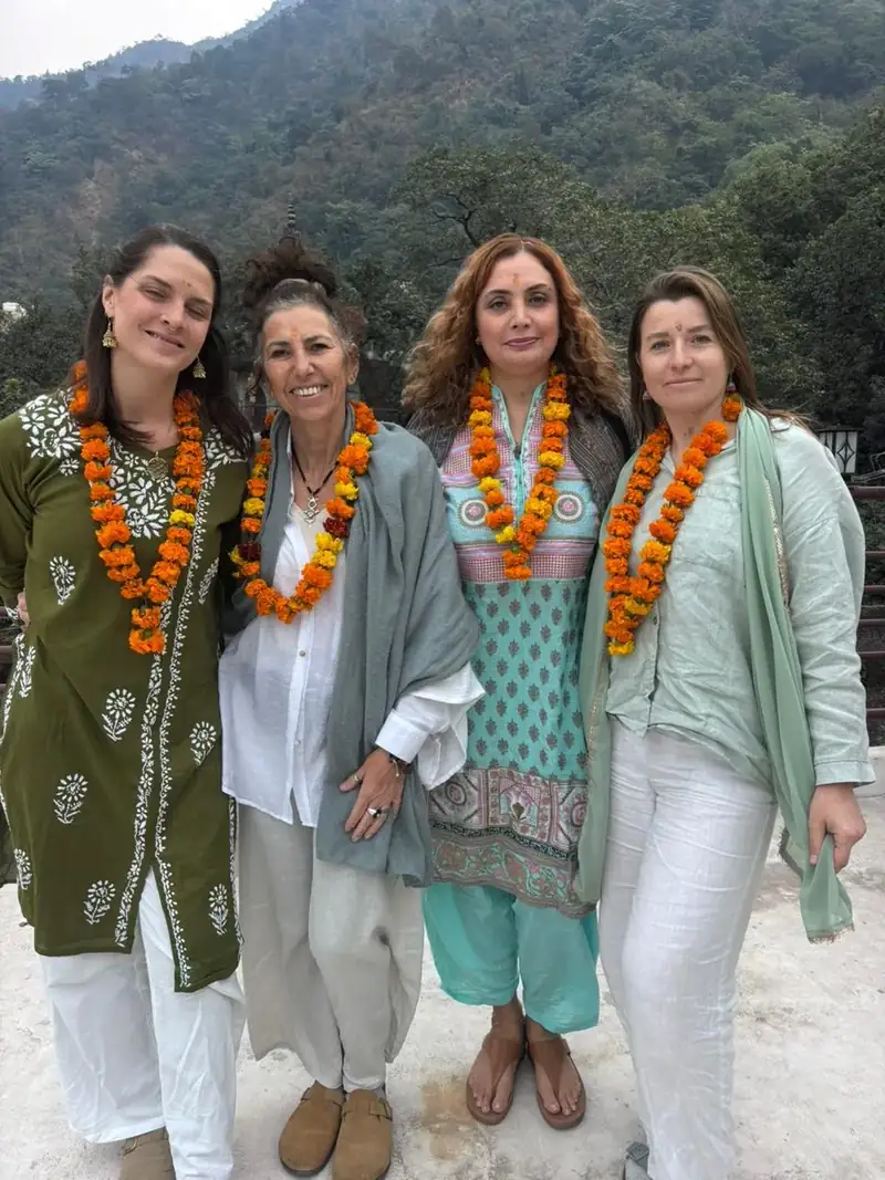 Four women in Indian dress with marigold garlands on Rishikesh hillside at Sri Yoga Ashram